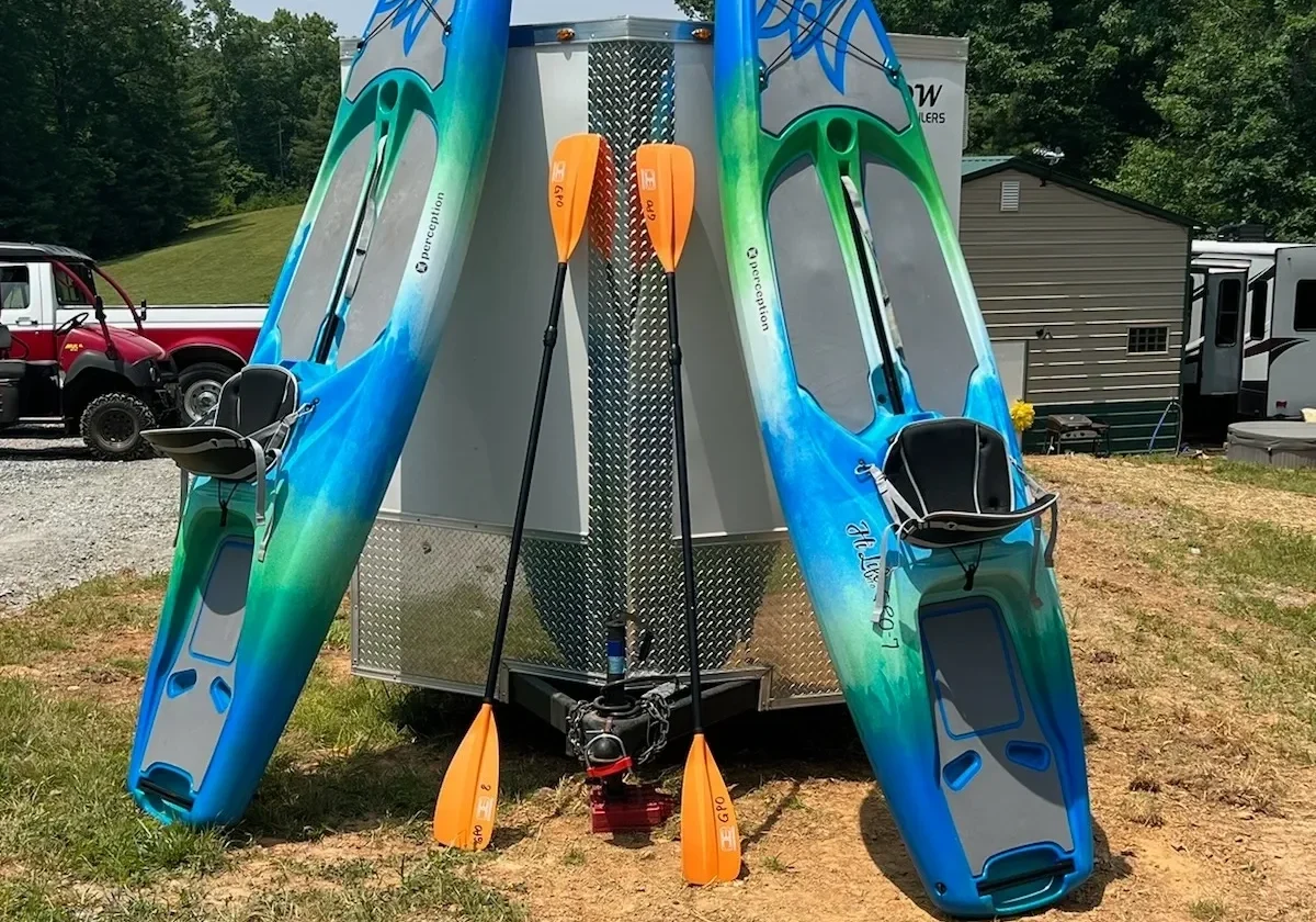 A trailer with three boats on it parked in the grass.